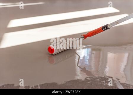 Needle roller for self-leveling floors. Leveling the floors with a cement mixture. Stock Photo