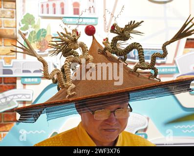 Shanghai, China. 28th Jan, 2024. An inheritor of intangible cultural heritage shows his hat under the theme of 'Year of the Dragon' during an exhibition of Chinese New Year customs at Shanghai Mass Art Center in Shanghai, east China, Jan. 28, 2024. Hundreds of exhibits including photos and unique products of Shanghai have been displayed at the exhibition to show Chinese New Year customs in Shanghai. Credit: Liu Ying/Xinhua/Alamy Live News Stock Photo