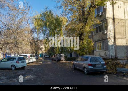 few cars parked in front of multistory residential apartment building at sunny November day Stock Photo