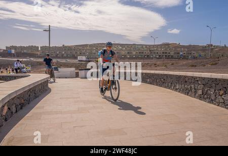 Tourist riding hired electric bicycles along the Playa Blanca trail on a sunny day on the canary Island of Fuerteventura. Stock Photo