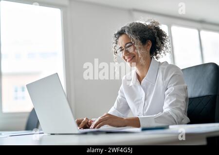 Smiling senior professional woman using laptop working in business office. Stock Photo