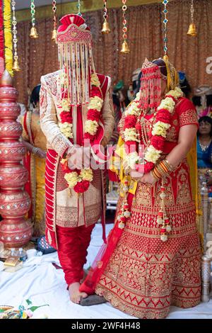 A Hindu bride & groom in traditional dress stand on a stone as part of their wedding ceremony. In and Shakti temple in Queens, New York. Stock Photo