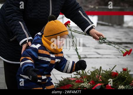 A child lays flowers at the eternal flame in memory of the victims of the siege of Leningrad at the Piskarevskoye Memorial Cemetery in St. Petersburg. St. Petersburg celebrates an important historical date, 80 years since the complete liberation of Leningrad from the fascist blockade. Stock Photo