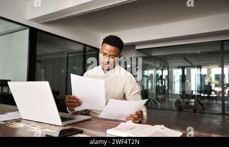 Busy African American lawyer checking documents working at laptop in office. Stock Photo