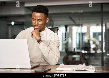 Busy African business man thinking on online investment working on laptop. Stock Photo