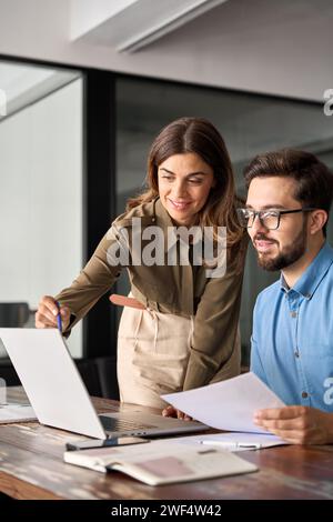 Professional woman manager explaining corporate software helping young employee. Stock Photo