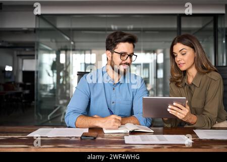Professional happy manager showing work plan using tab helping employee. Stock Photo