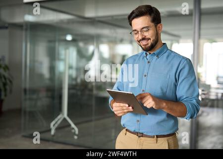Smiling busy young business man manager using tablet standing in office. Stock Photo