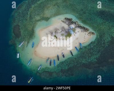 Aerial view of a small tropical island with dense forest and white ...