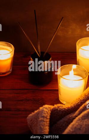 Soothing Aromatherapy with Reed Diffuser, Blanket and Candles on Wooden Table Stock Photo