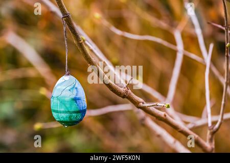 An egg for Easter hangs forgotten on a branch on a barren bush in winter Stock Photo