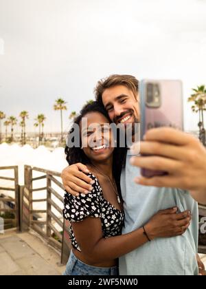 Diverse heterosexual couple in love taking a selfie in a city during vacation Stock Photo