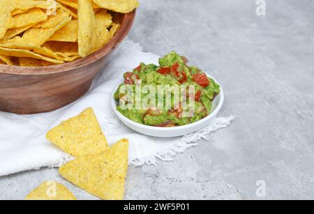 Close up of tortilla in a wooden bowl and fresh guacamole dip on grey marble table Stock Photo