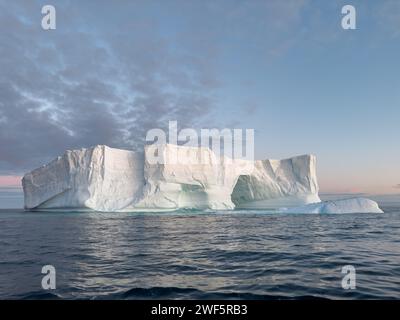 A huge high breakaway glacier drifts in the southern ocean off the coast of Antarctica at sunset, the Antarctic Peninsula, the Southern Arctic Circle Stock Photo