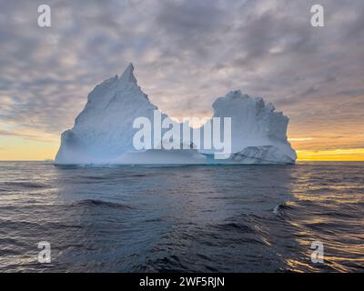 A huge high breakaway glacier drifts in the southern ocean off the coast of Antarctica at sunset, the Antarctic Peninsula, the Southern Arctic Circle Stock Photo