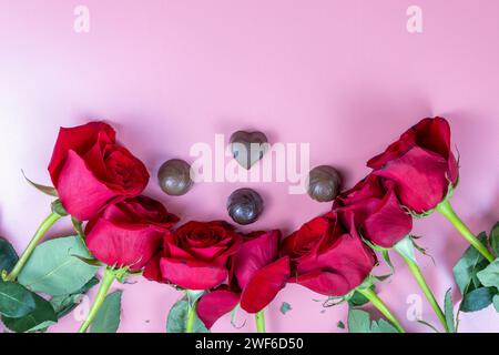 Delicious chocolate sweets and red roses on a pink background Stock Photo