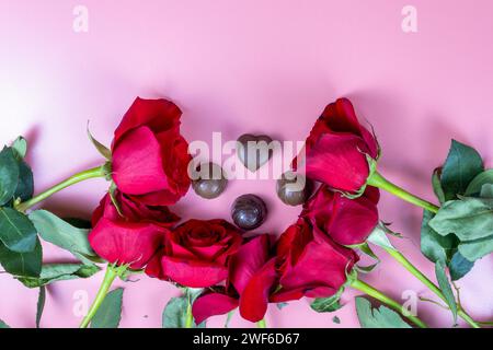 Delicious chocolate sweets and red roses on a pink background Stock Photo