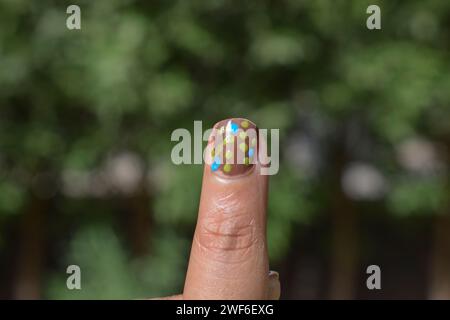 Closeup of Nail art designs, Handmade dots nail design on female index finger. Nail art with colorful dots nail design Stock Photo