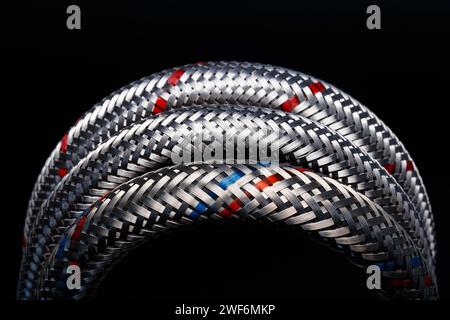 Flexible metal braided hose for connecting hot and cold water. Macro photography Stock Photo