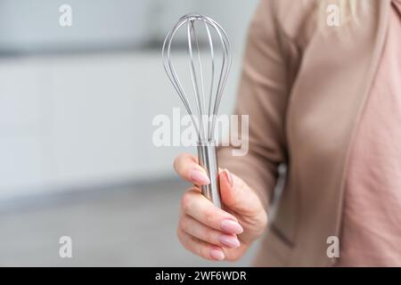 Female holding in hand whisk isolated on white background. Clipping Path. Full depth of field. Stock Photo