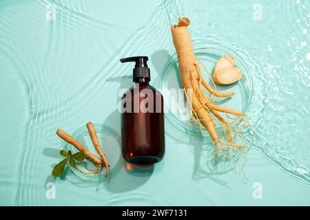 Top view of empty cosmetic bottles and fresh ginseng placed on water background. Mockup for advertising ginseng root extract cosmetics. Flat lay. Stock Photo