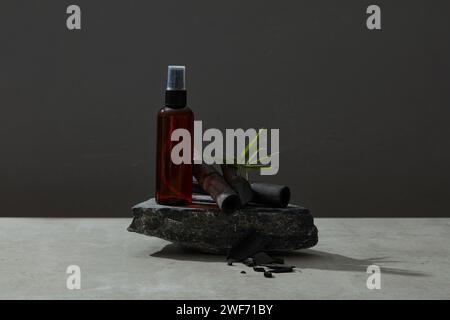 Empty plastic bottles set on stone on black background with bamboo charcoal and green leafs. Advertising photo. Mockup, front view. Stock Photo