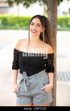 Beautiful young woman looking at camera smiling outdoors Stock Photo