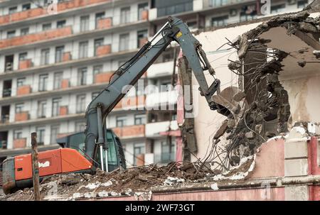 Excavator demolish or remove old ruined building in rainy day. Old house demolition on construct cite for renovation new housing in modern city. Stock Photo