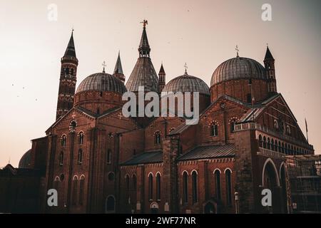 The domes and spires of the Basilica of Saint Anthony glow under the warm sunset sky in Padua, Italy, a beacon of Venetian architecture. Stock Photo