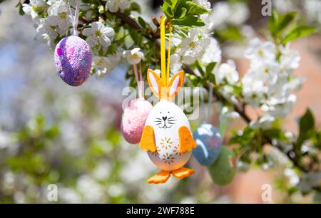 decorative easter eggs and rabbit hanging on flowering tree branch Stock Photo