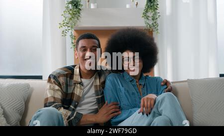 Happy family African American couple spouses married man woman ethnic smiling husband boyfriend girlfriend wife cuddling smile posing on sofa couch at Stock Photo
