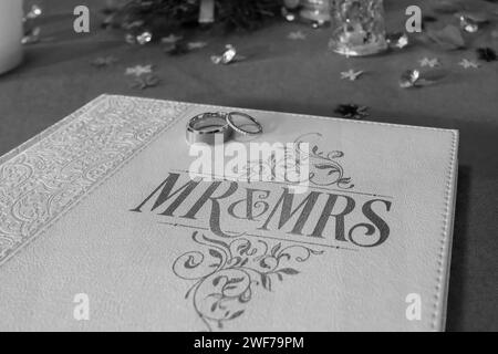 A close view of wedding rings on the 'Mr & Mrs' embossed guestbook at a reception Stock Photo