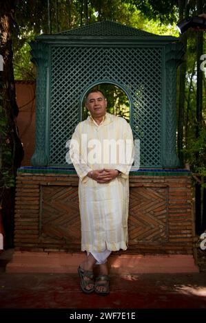 A man wearing traditional Middle eastern dress stands in a Moroccan garden. Stock Photo