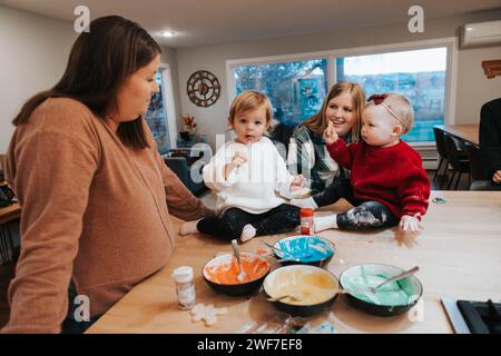 Moms and daughters gather, ready to frost cookies, joy Stock Photo