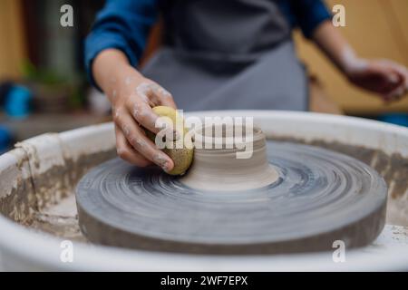 Close up woman doing pottery on pottery wheel. Child creative activities and art. Boy making pottery with mom, having fun. Happy family moment. Stock Photo