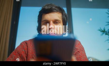 Low angle shot of young man surfing internet on mobile phone, checking email, reading media news, scrolling social networks, using mobile applications Stock Photo
