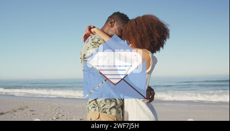 Image of email envelope digital icon over couple in love hugging on beach Stock Photo