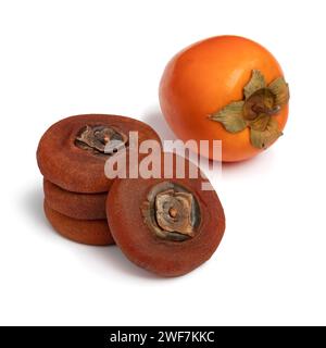 Stack of dried kaki persimmon and a fresh ripe one isolated on white background close up Stock Photo