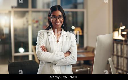 Night, arms crossed and face of happy woman, office consultant or HR manager happy for workplace empowerment. Pride, portrait and Indian person Stock Photo
