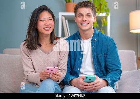 Portrait Of Smiling Multiracial Man And Woman With Cell Phone Device.Interior Stock Photo