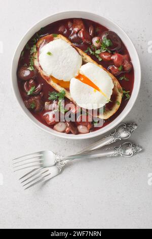 Eggs meurette or poached eggs with red wine sauce closeup on the plate on the table. Vertical top view from above Stock Photo