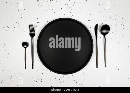 Christmas composition, black plate and cutlery, silver stars confetti on white background. Christmas, new year, winter concept. Stock Photo