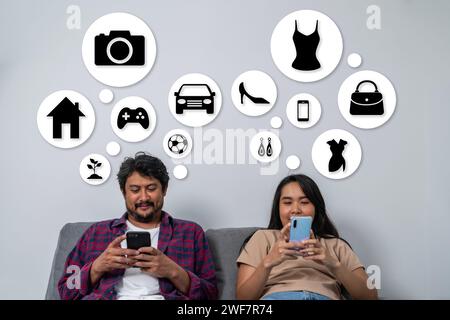 A young couple, each using a smartphone, is searching for things of interest while sitting on the sofa at home Stock Photo