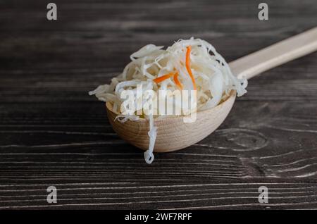 Sauerkraut in a wooden spoon on a brown wooden base Stock Photo