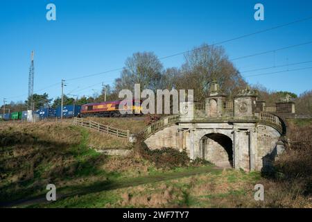 COLWICH, STAFFORDSHIRE, ENGLAND. JANUARY 2024. EWS locomotive train travelling over an ornate railway bridge on the West Coast mainline railway. Stock Photo