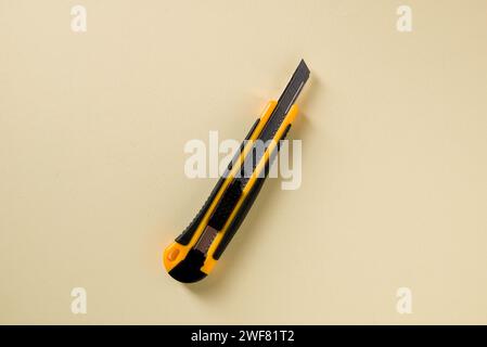 Utility knife with yellow and black handle on a yellow background Stock Photo