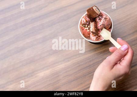 Top view of ice cream in paper cup, woman hand with spoon. Soft view Stock Photo
