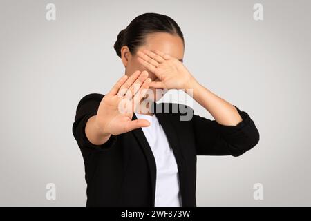 Professional Asian businesswoman in a black suit makes a stop gesture with her hands Stock Photo