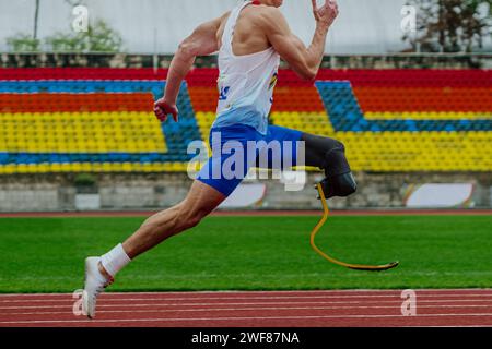 male runner sprinter on prosthesis running stadium track, disabled athlete para athletics competition Stock Photo