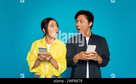 Shocked woman and man holding smartphones with surprised expressions Stock Photo